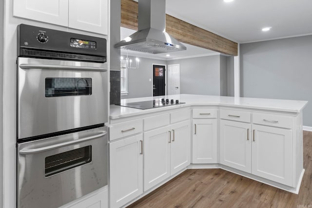 kitchen featuring light wood-type flooring, island exhaust hood, stainless steel double oven, white cabinets, and black electric cooktop