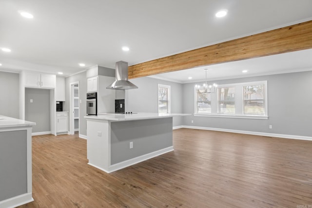 kitchen featuring oven, baseboards, wall chimney range hood, light wood-style floors, and white cabinetry