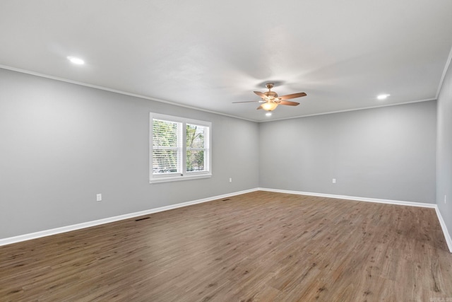 spare room with baseboards, wood finished floors, a ceiling fan, and crown molding