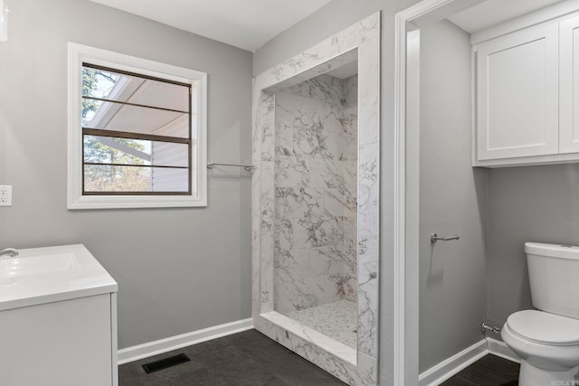 full bathroom featuring visible vents, baseboards, toilet, tiled shower, and vanity