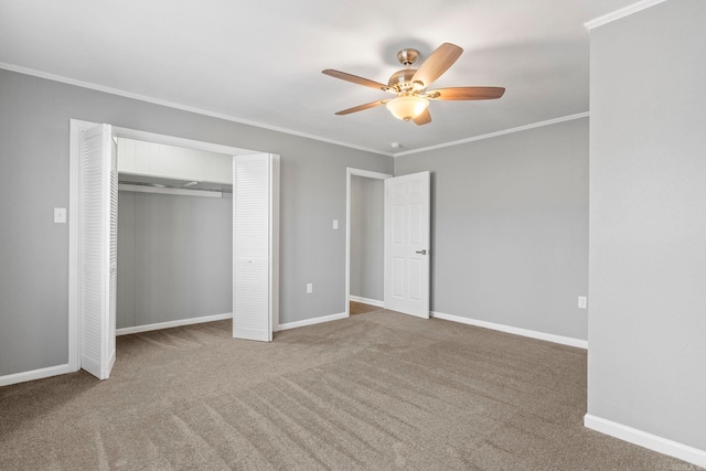 unfurnished bedroom with baseboards, carpet floors, ceiling fan, a closet, and crown molding