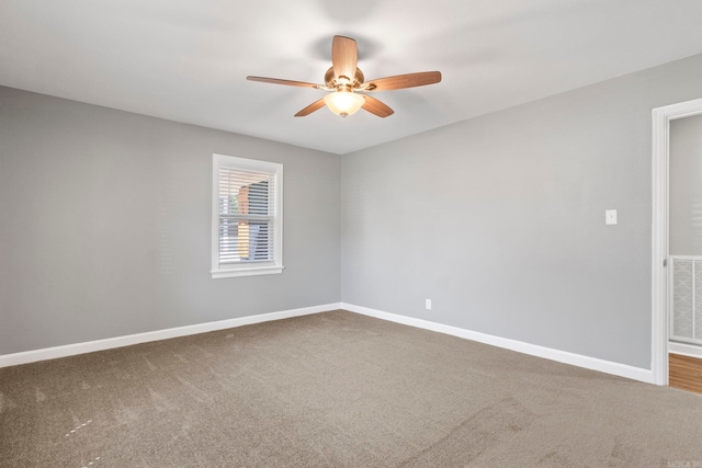 carpeted empty room with visible vents, baseboards, and a ceiling fan