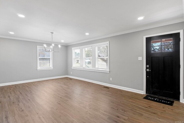 foyer entrance with a chandelier, crown molding, baseboards, and wood finished floors