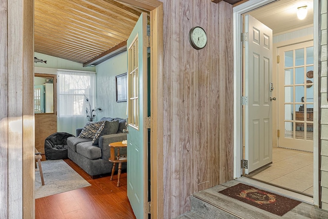 hall with vaulted ceiling, wooden walls, and wood finished floors