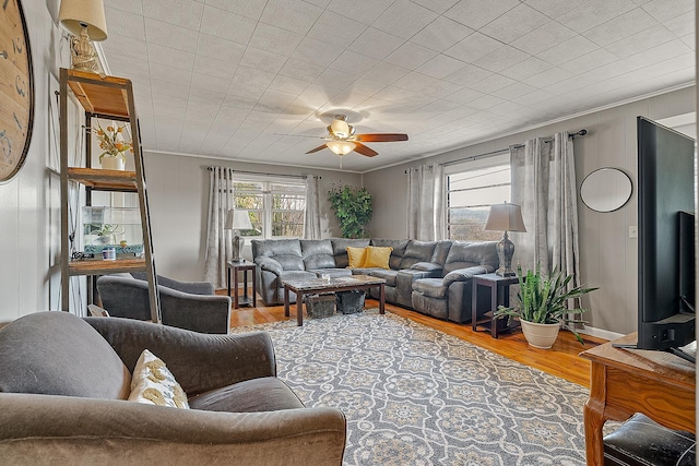 living area featuring ceiling fan, baseboards, wood finished floors, and ornamental molding