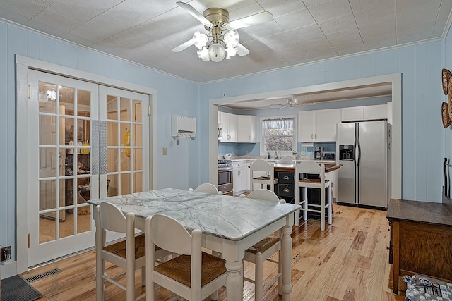 dining room with visible vents, a ceiling fan, french doors, light wood-style floors, and crown molding