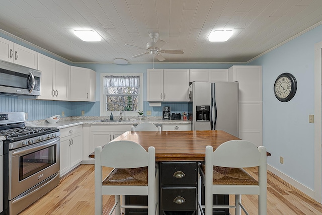 kitchen featuring stainless steel appliances, light countertops, ceiling fan, and a sink