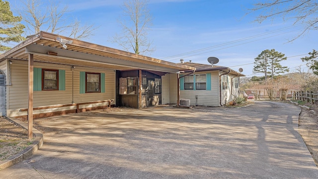 rear view of house featuring concrete driveway and fence