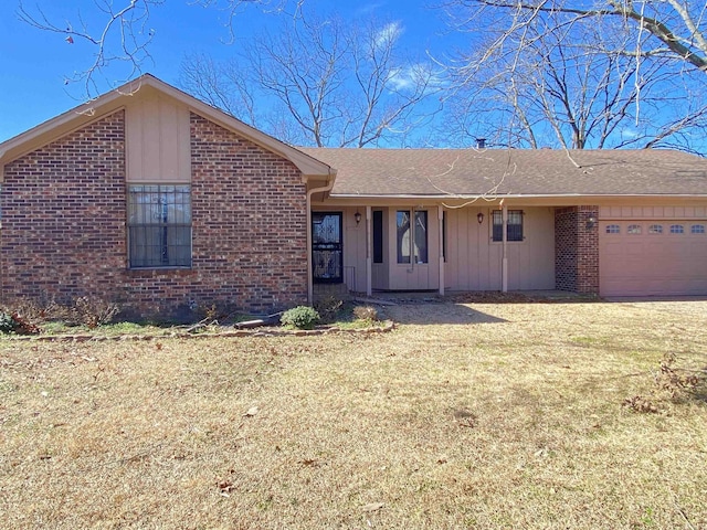 ranch-style home featuring a garage, brick siding, board and batten siding, and a front lawn