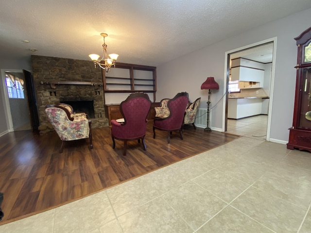 tiled living room with a notable chandelier, a healthy amount of sunlight, a textured ceiling, and baseboards