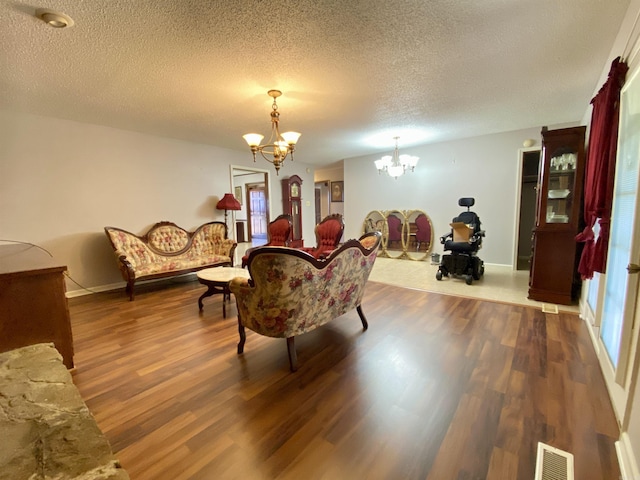 sitting room with an inviting chandelier, wood finished floors, visible vents, and a textured ceiling