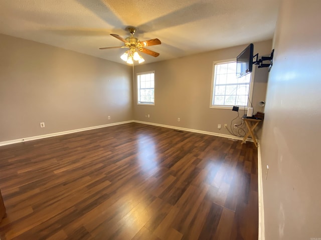 empty room with baseboards, a textured ceiling, dark wood-style floors, and a ceiling fan