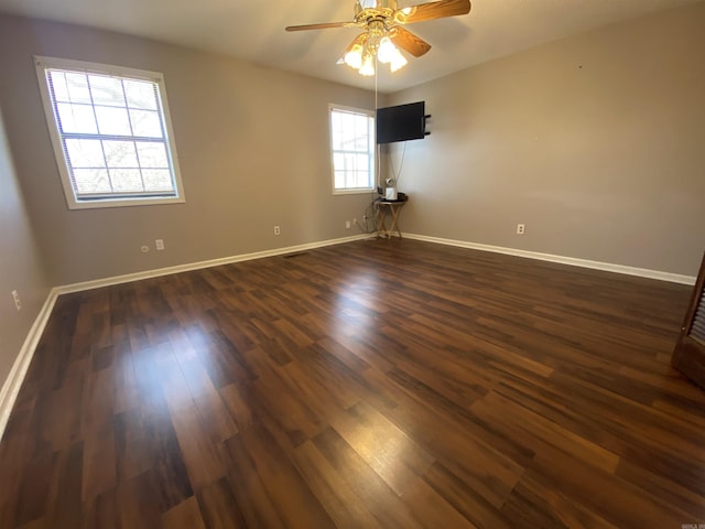 empty room featuring baseboards, dark wood-type flooring, and a ceiling fan