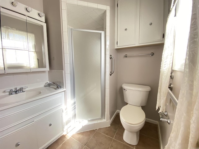 full bath with vanity, baseboards, a stall shower, tile patterned flooring, and toilet