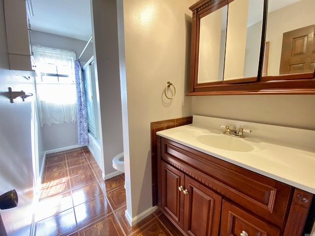 bathroom with toilet, shower / washtub combination, tile patterned flooring, baseboards, and vanity