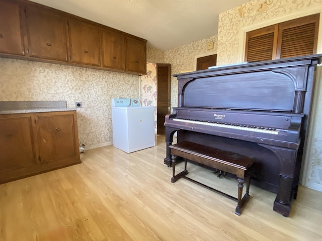 interior space featuring baseboards, wallpapered walls, washer and clothes dryer, and light wood-style floors