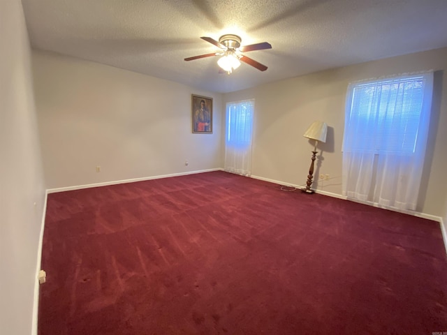 empty room with baseboards, a textured ceiling, ceiling fan, and dark colored carpet