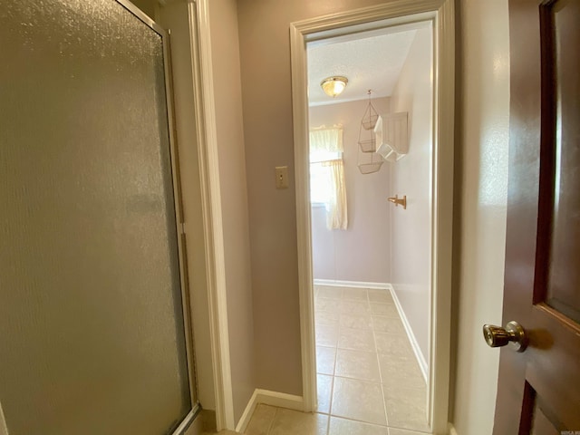 bathroom with tile patterned floors, baseboards, a textured ceiling, and a stall shower