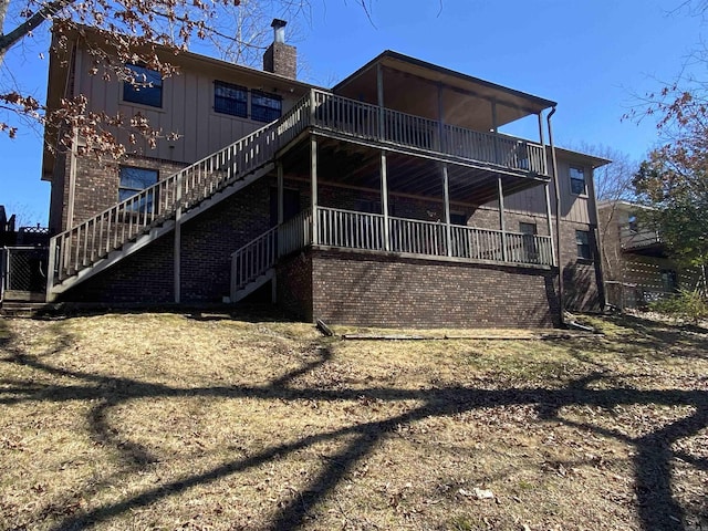 rear view of house featuring stairway, brick siding, and a chimney