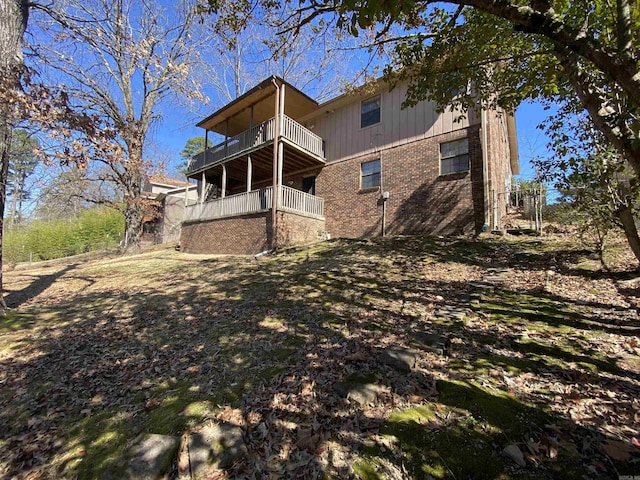 rear view of house featuring brick siding and a balcony