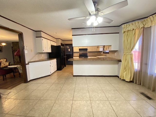 kitchen with visible vents, a peninsula, a sink, black fridge with ice dispenser, and stainless steel gas range oven