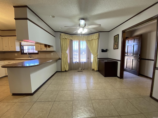 kitchen with ceiling fan, ornamental molding, light tile patterned floors, a peninsula, and white cabinets