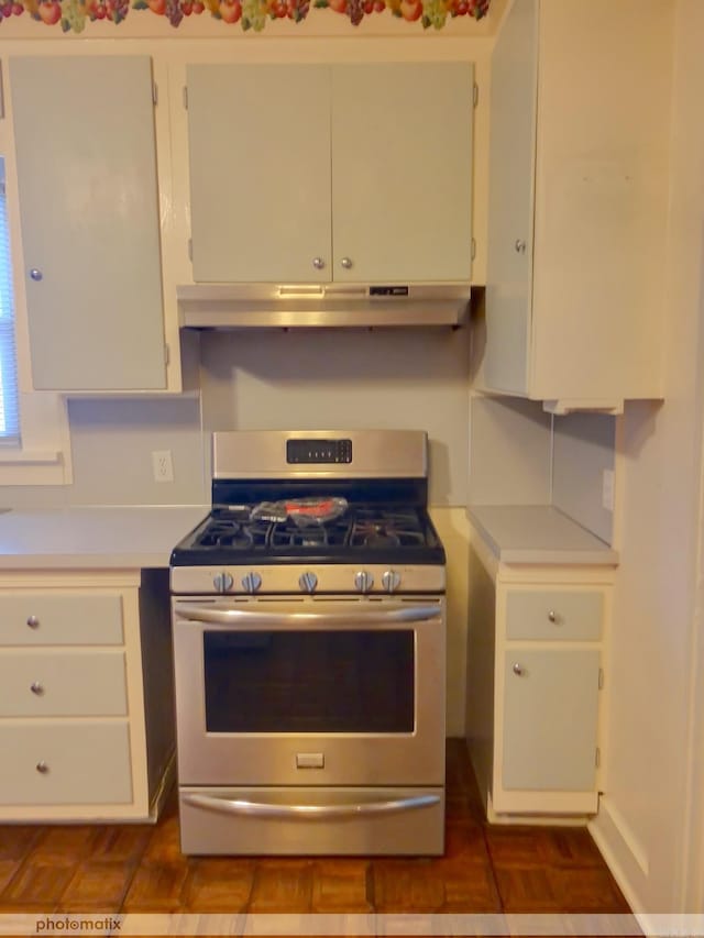 kitchen featuring white cabinetry, light countertops, gas stove, and under cabinet range hood