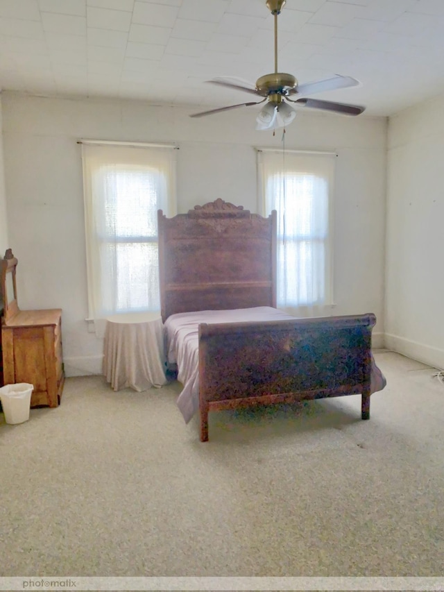 carpeted bedroom featuring baseboards, multiple windows, and a ceiling fan