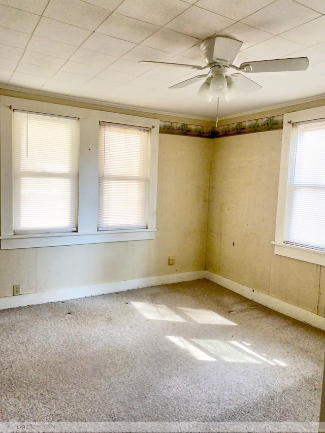 carpeted spare room with crown molding, a ceiling fan, and baseboards