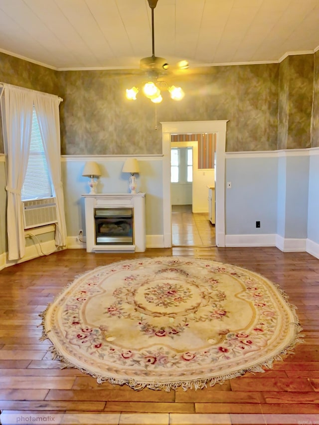 interior space with a glass covered fireplace, cooling unit, wood-type flooring, wainscoting, and ceiling fan