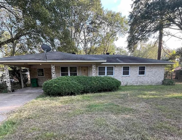 view of front facade featuring brick siding, driveway, an attached carport, and a front yard