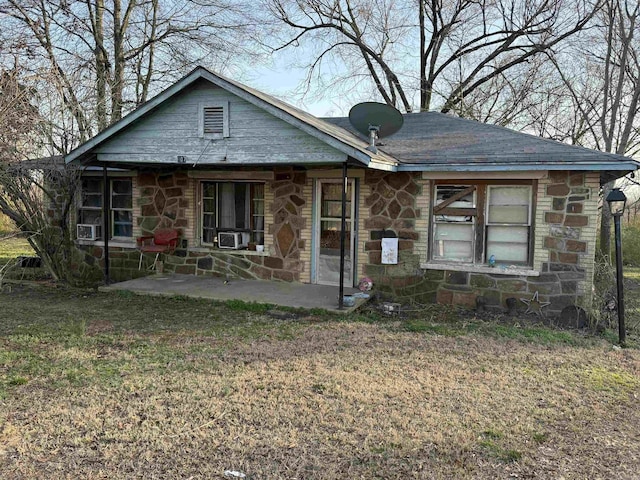 view of front of house featuring a front yard, cooling unit, stone siding, and a patio