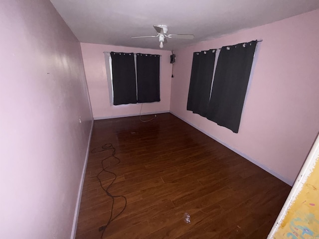 unfurnished room featuring dark wood finished floors, baseboards, and ceiling fan