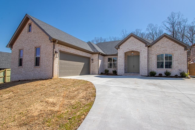 view of front of home with brick siding, concrete driveway, a front yard, roof with shingles, and a garage