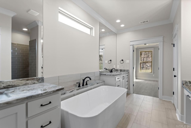 bathroom featuring vanity, a freestanding tub, a healthy amount of sunlight, and visible vents