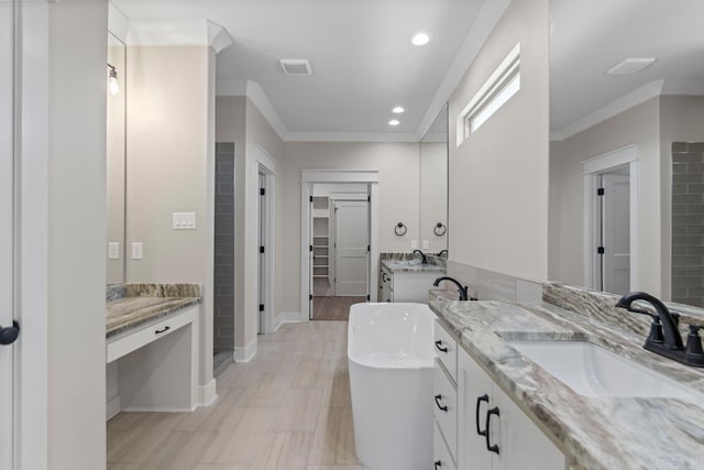 bathroom with ornamental molding, a freestanding bath, and a sink