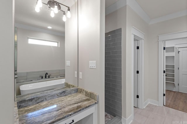 full bathroom featuring tiled shower, vanity, a spacious closet, and crown molding