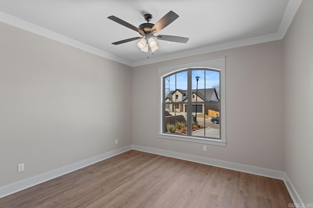 spare room featuring ceiling fan, wood finished floors, baseboards, and ornamental molding