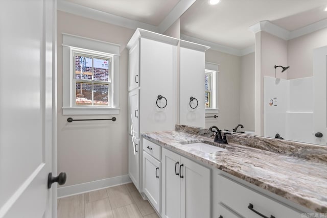 full bath with vanity, crown molding, baseboards, and walk in shower