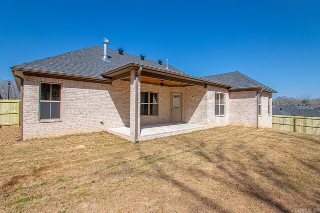 rear view of property with a patio, fence, a lawn, and a shingled roof