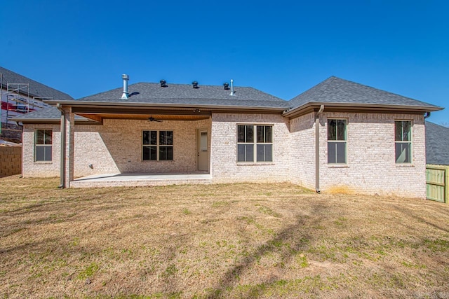 rear view of house with a lawn, roof with shingles, a patio, and fence