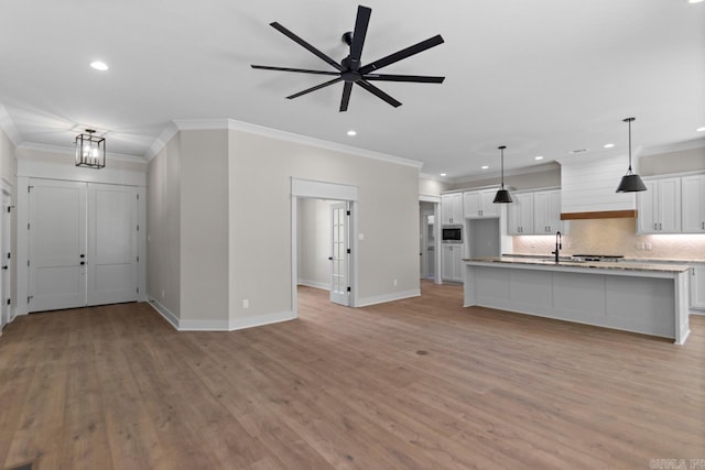 interior space with light wood-type flooring, baseboards, ornamental molding, and a ceiling fan