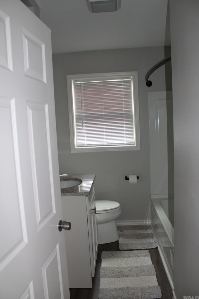 bathroom with toilet, shower / tub combination, wood finished floors, baseboards, and vanity