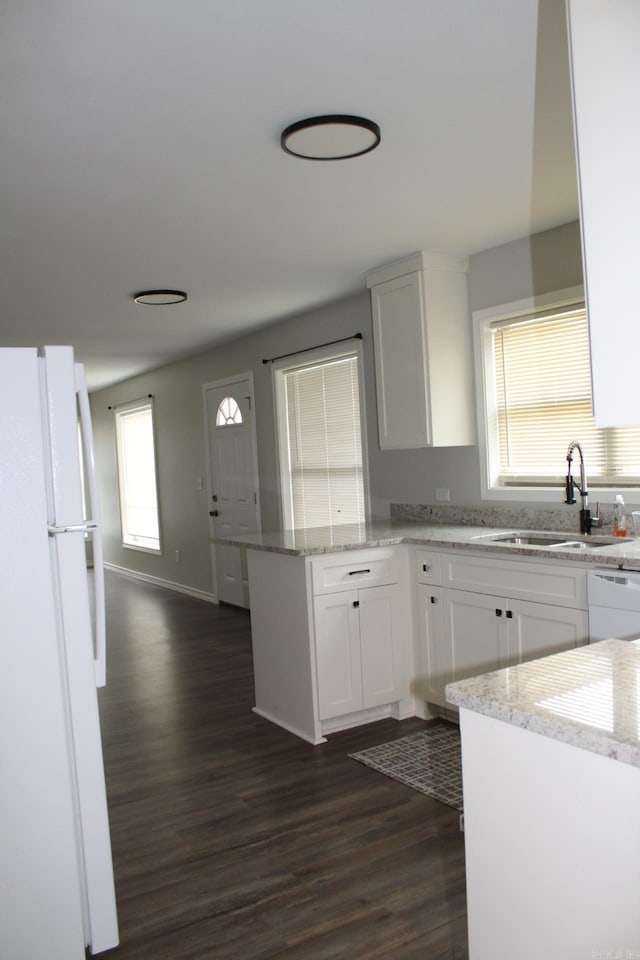 kitchen with a sink, dark wood finished floors, white cabinetry, white appliances, and a peninsula