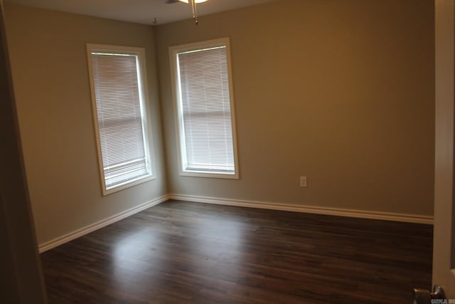 empty room featuring a ceiling fan, dark wood-type flooring, and baseboards