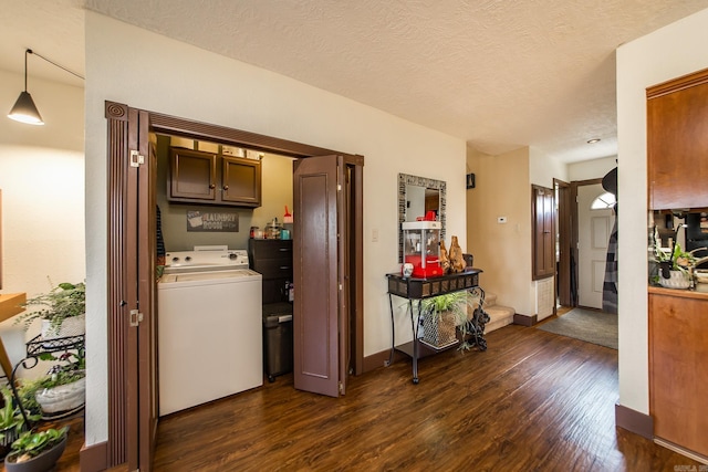 washroom featuring washer / clothes dryer, a textured ceiling, dark wood-style floors, cabinet space, and baseboards