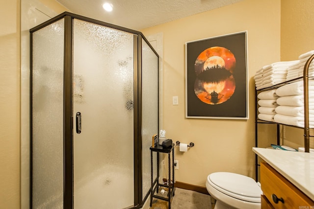 bathroom with toilet, a stall shower, a textured ceiling, baseboards, and vanity