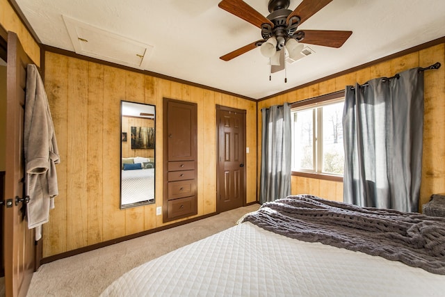 bedroom featuring ornamental molding, wood walls, light colored carpet, attic access, and ceiling fan