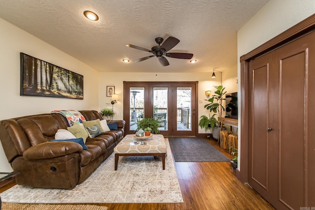 living area featuring a ceiling fan, wood finished floors, and a textured ceiling