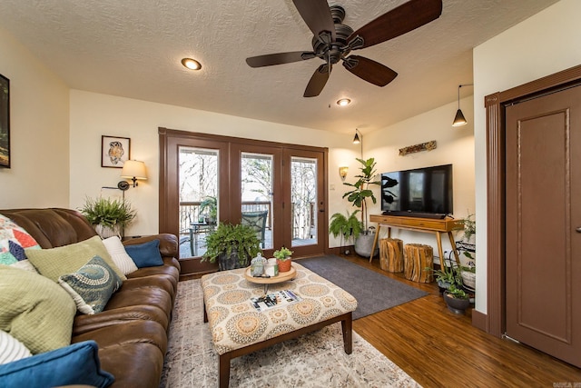 living area featuring a textured ceiling, lofted ceiling, ceiling fan, and wood finished floors